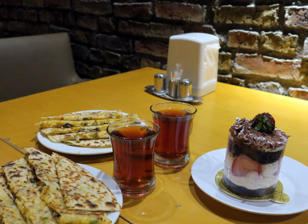 Dinner of turkish traditional vegetable tortillas and black tea with dessert cake