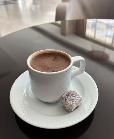 Turkish coffee in a small white cup with Turkish delight