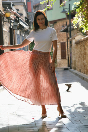 Fashionable woman 51 years old in a light beige skirt and white t-shirt posing in the sunlight in Antalya Turkeyの写真素材