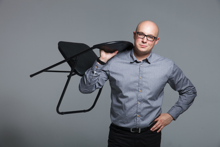 Studio portrait of business man with a chair on a grey backgroundの写真素材