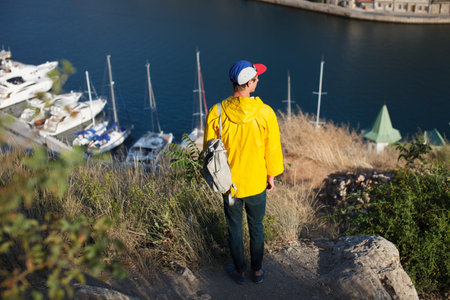 Young male hiker with backpack walking to the mountain