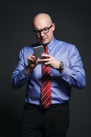 Studio portrait of emotional businessman talking on phone on a dark backgroundの写真素材