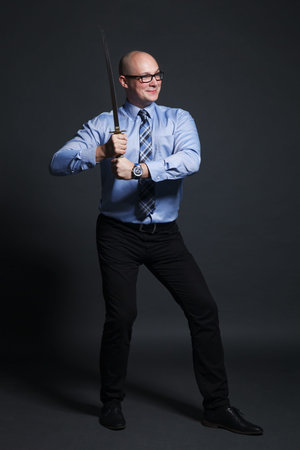 Studio portait of a businessman that holding katana sword on grey background
