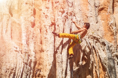 Mature mrock climber on the wall against the blue sky and mountains - stock photo.の写真素材