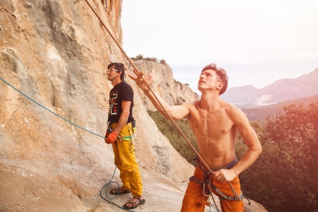 Two rock climbers with belay rope on the cliff against blue sky and mountains. Stock image.の写真素材