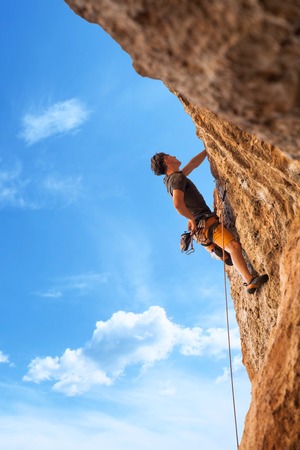 Male rock climber on the wall against the blue sky and mountains. Active living, lifestyle and sport concept - stock photo.の写真素材