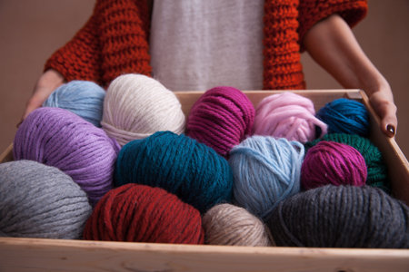Woman holding a basket witn colorful yarn ball and knitting needles. Close-up vertical photo....