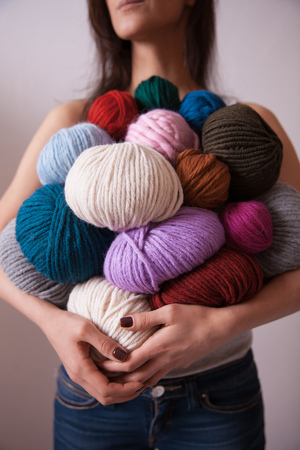 Young pretty woman holding many colorful  yarn clews. Close-up vertical photo. Concept of freelance creative working and livingの写真素材