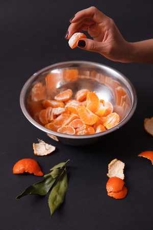 Woman holding a piece of mandarin over the metal dish. Concept of healthy foodの写真素材