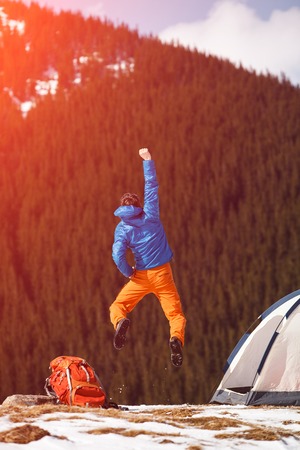 Mountain hiker celebrating success and do the joy jumping on mountain peak against the pine trees. Concept of free living and traveling, active leisure, health care and well being.の写真素材