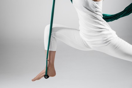 An adult woman practices different inversion - anti-gravity yoga positions in a bright well lit studio.の写真素材