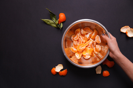 Woman holding a piece of mandarin over the metal dish. Concept of healthy foodの写真素材