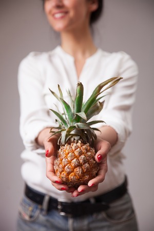 Young woman hands with pineaple - closeup photo. Concept of vegetarian dieting, raw food ingredients, healthy and joyful livingの写真素材
