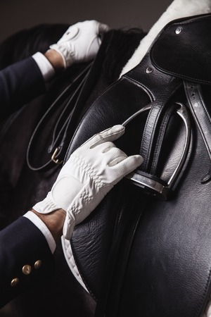 Male horse rider prepearing horse for the riding - install and check the equipment. Unrecognizable. Concept of animal loving and having hobbyの写真素材