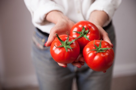 Young woman hands with tomatoes - closeup photo. Concept of vegetarian dieting, raw food ingredients, healthy and joyful livingの写真素材