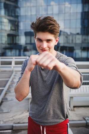 Athlete warming up and boxing on downtown against office buildings before urban running. Concept of active living, freelance, remote business, healthcare and wellbeingの写真素材