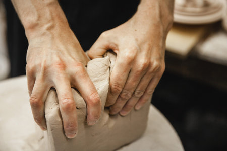 Adult male potter master preparing the clay on table. Front view, closeup, hands only,...