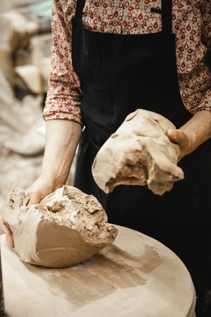 Adult male potter master preparing the clay on table. Front view, closeup, hands only, unrecognizable. Art and business, hobby and freelance working concept.の写真素材
