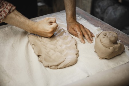 Adult male potter master mashing the clay on table. Front view, closeup, hands only, unrecognizable. Art and business, hobby and freelance working concept.の写真素材