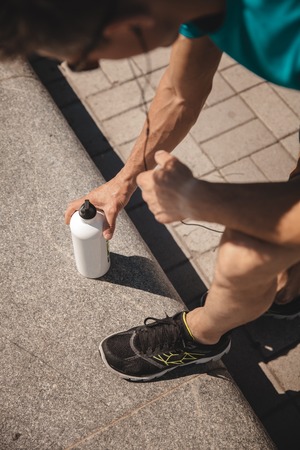 Unrecognizable male athlete drinking water after urban running. Closeup, Top view, focus on hands. Concept of hard working and active living, freelance, remote business, healthcare and wellbeingの写真素材