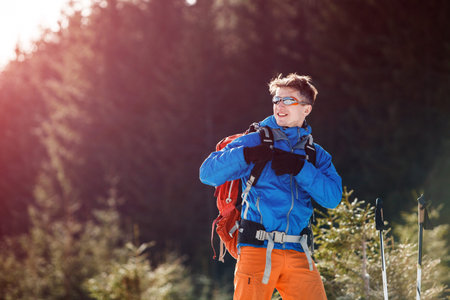 Male hiker passing winter mountains against the pine forest. Concept of success living and free traveling, active leisure, health care and well being.の写真素材