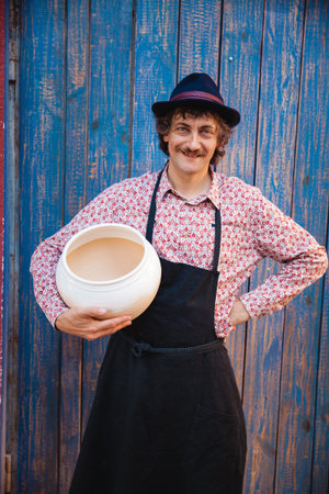 Potter master with clay pot on pottery yard. Front view, closeup. Art and business, hobby and freelance working concept.の写真素材