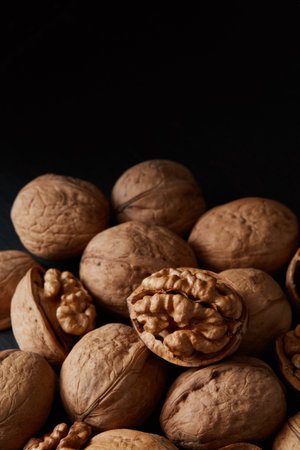 Close-up crop of walnuts and kernels on a black backdrop. Healthy raw snack or organic vegetarian...
