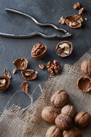 Walnuts and kernels with burlap fabric on a grey concrete backdrop with vintage nutcracker. Healthy raw snack or organic vegetarian meal ingredientsの写真素材