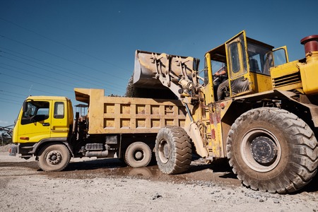 Front loading excavator works in a hot outdoors slag dump. Heavy industrial metallurgical foggy landscapeの写真素材