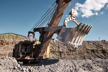 Huge quarry bucket excavator works in a hot outdoors slag dump. Heavy industrial metallurgical foggy landscapeの写真素材