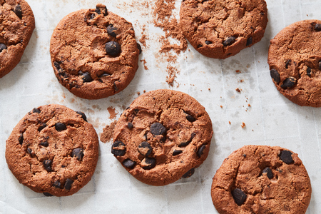Flatview of handcrafted chocolate cookies with chocolate chips on baking paper. Natural handmade organic snakes for healthy breakfastの写真素材