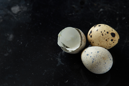 Some quail eggs and eggshells on black rusty background. Concept of healthy nutritions and natural cuisineの写真素材