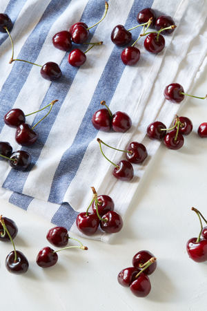 A lot of scattered sweet cherries on the striped table napkin. Vegan ration, healthy natural eating, raw food ingredients and cookingの写真素材