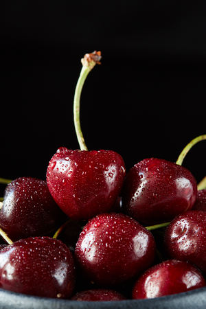 A pile of sweet cherries isolated on the black background. Macro view, extreme close-up. Vegan ration, healthy natural eating, raw food ingredients and cookingの写真素材