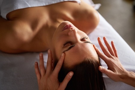 Close-up of female enjoying relaxing head and face massage made by masseuse with forearms and cubits in cosmetology spa centre. Body care, skin care, wellness, wellbeing, beauty treatment concept.の写真素材