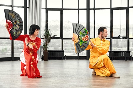 Couple of senior masters practicing qi qong taijiquan at studio. Breathing exercise and martial art moves, traditional chinese qi energy management gymnastics.の写真素材