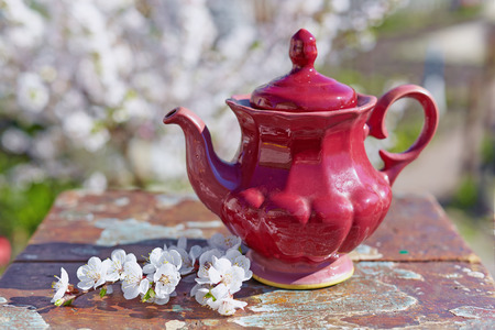 Old teapot on a wooden table. Bright spring day. Shabby chic style.の写真素材