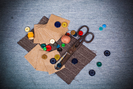 Scissors, threads, buttons, pieces of felt and fabric on a gray background. Needlework abstract background in retro style.の写真素材