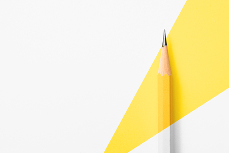 Beautiful top view close up macro photography of wooden yellow pencil isolated on yellow and white paper with copy space to look minimalism and clean. Flash light made smooth shadow from yellow pencil.の写真素材