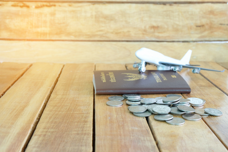 Money saving concept for vacation with coins stack, passport, and aircraft toy on the wooden backgroundsの写真素材