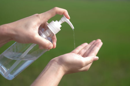 woman hands using gel alcohol sanitizer cleaning her hands, to prevent the virus and bacterias, she...