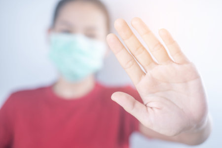 Asian woman wears hygiene protective mask to protect COVID-19. Show hand, don't come in....