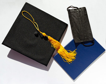 Graduate cap, blue diploma and black protective face mask on white background, protection from the virus while studying, new reality, new normal, Flat lay, top viewの写真素材