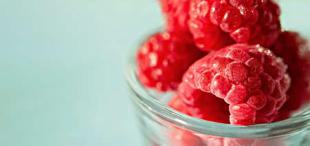 Frozen raspberries close-up in glass cup on blue background close-up, copy space, selective focus, Healthy raw food vegan, diet, berries antioxidants, macroの写真素材