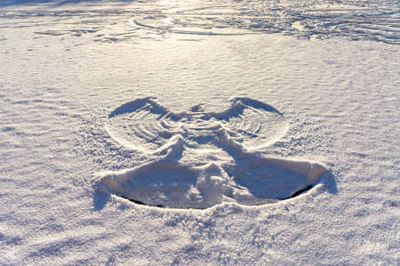 print of a snow angel on fresh white snow and frozen lake at sunset. Abstract background, Christmas, twinter fun, snowyの写真素材
