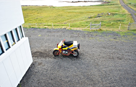 Yellow sidecar motorcycle parked next to the white hostel building road trip in Iceland, travel,...
