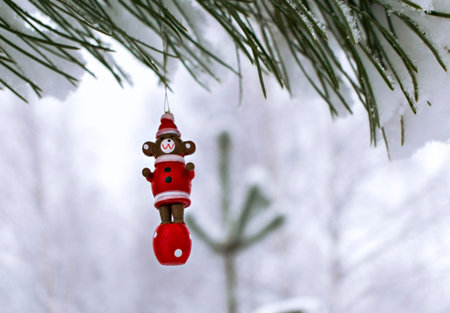 Christmas wooden toy bear on a snow-covered pine branch in the winter forest. Christmas background...
