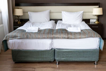 double bed with white bedclothing and towels in room in gray brown interior by the window hotel apartments modern designの写真素材