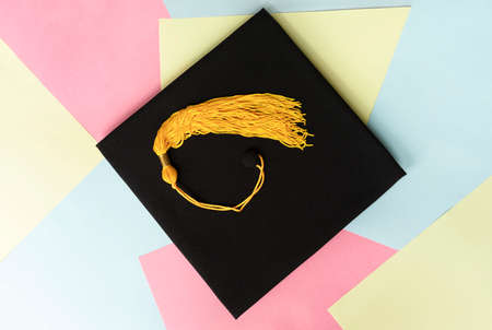 Black graduation cap or hat with yellow tassel on colorful pastel background education mortarboardの写真素材