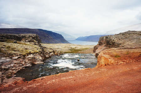 Scenic view of cliffs of Iceland against mountains and the North Atlantic Ocean and red ground beautiful landscape nature selective focusの写真素材